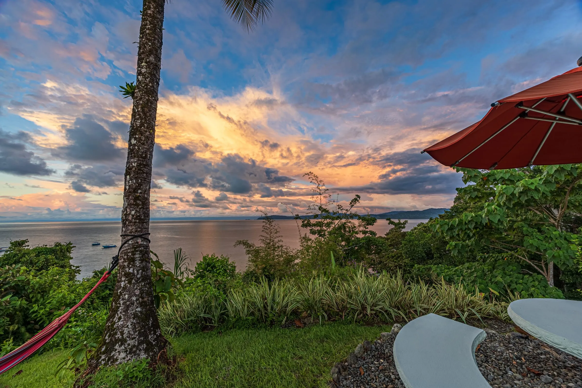 A hammock and a red umbrella in the garden at sunset